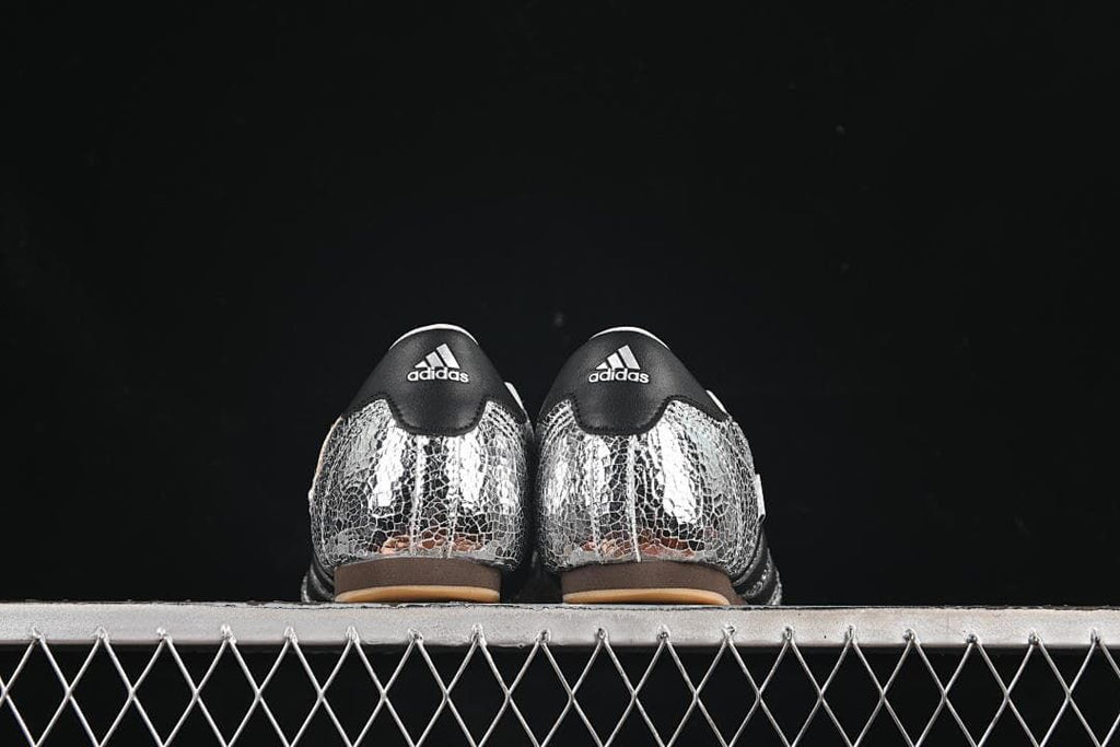 Back view of both shoes with black heel panels and silver patterned uppers.