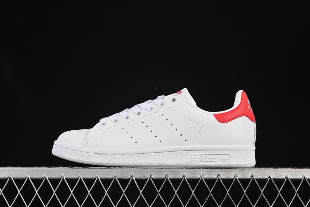 Side view of a white adidas Stan Smith sneaker with a red heel tab