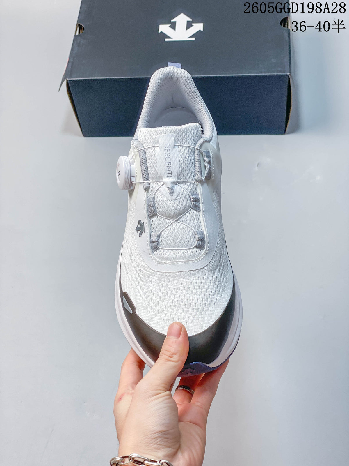 Top view of the white Descente running shoe with dial closure and cable lacing; image overlay shows code 2605GGD198A28 and size range 36–40.5.