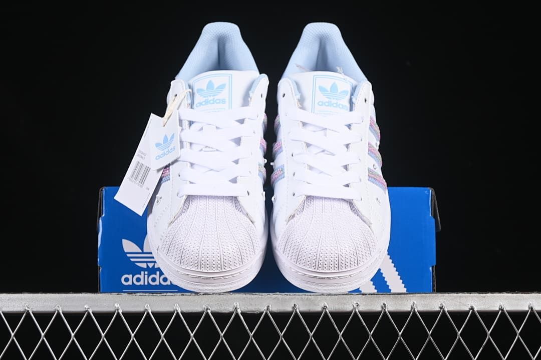 Front view of the white sneakers showing shell toes, laces, and pastel side stripes