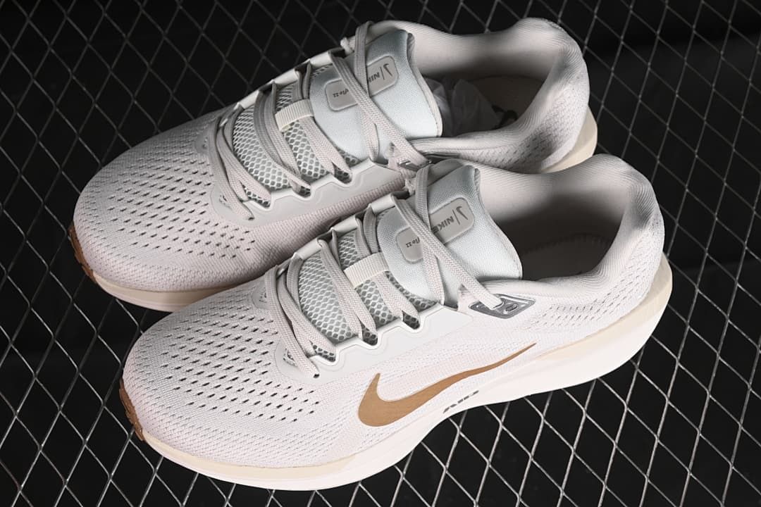 Pair of light-colored Nike Winflo 11 shoes with gold-tone accents.