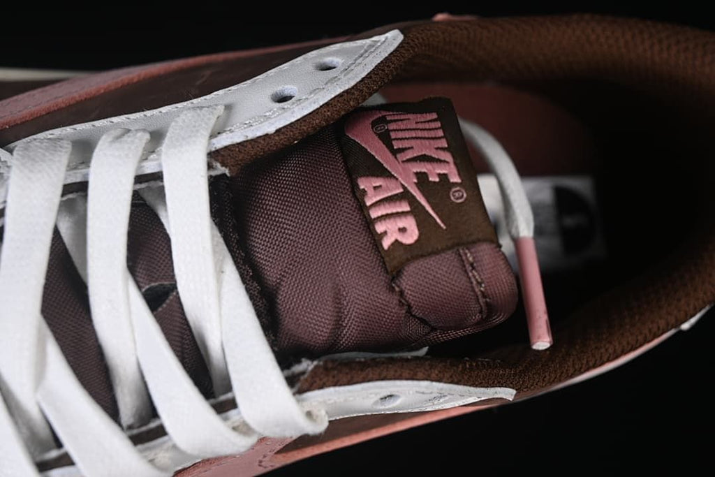 Close-up of the brown tongue with pink Nike Air branding and white laces.