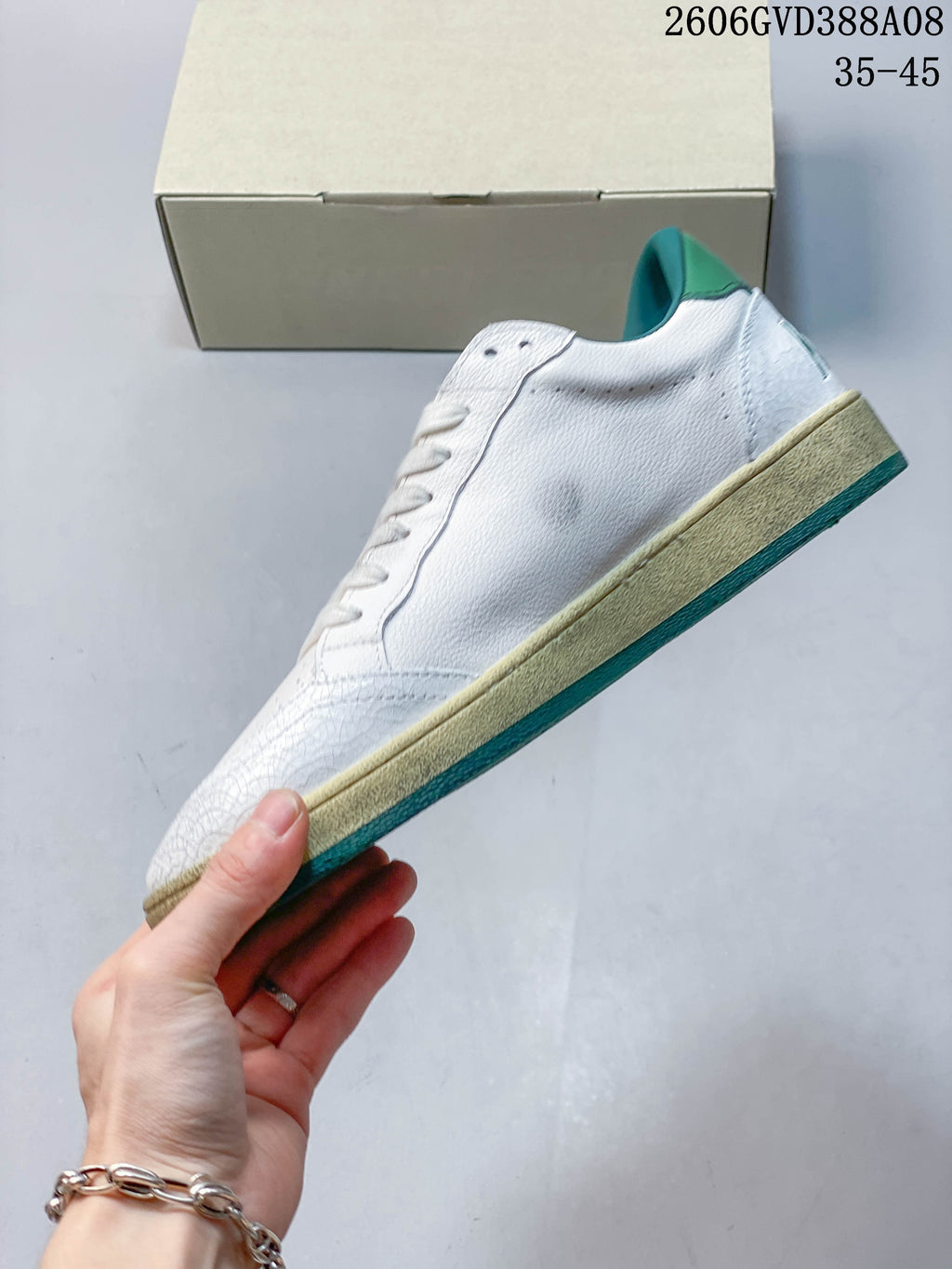Side profile of a white low-top sneaker with a beige-look midsole and teal outsole