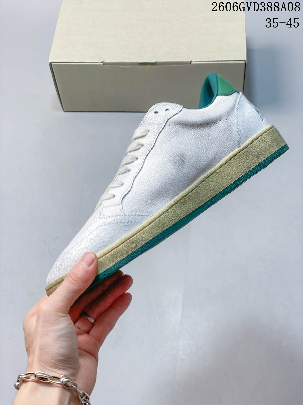 Side profile of a white low-top sneaker with a beige-look midsole and teal outsole