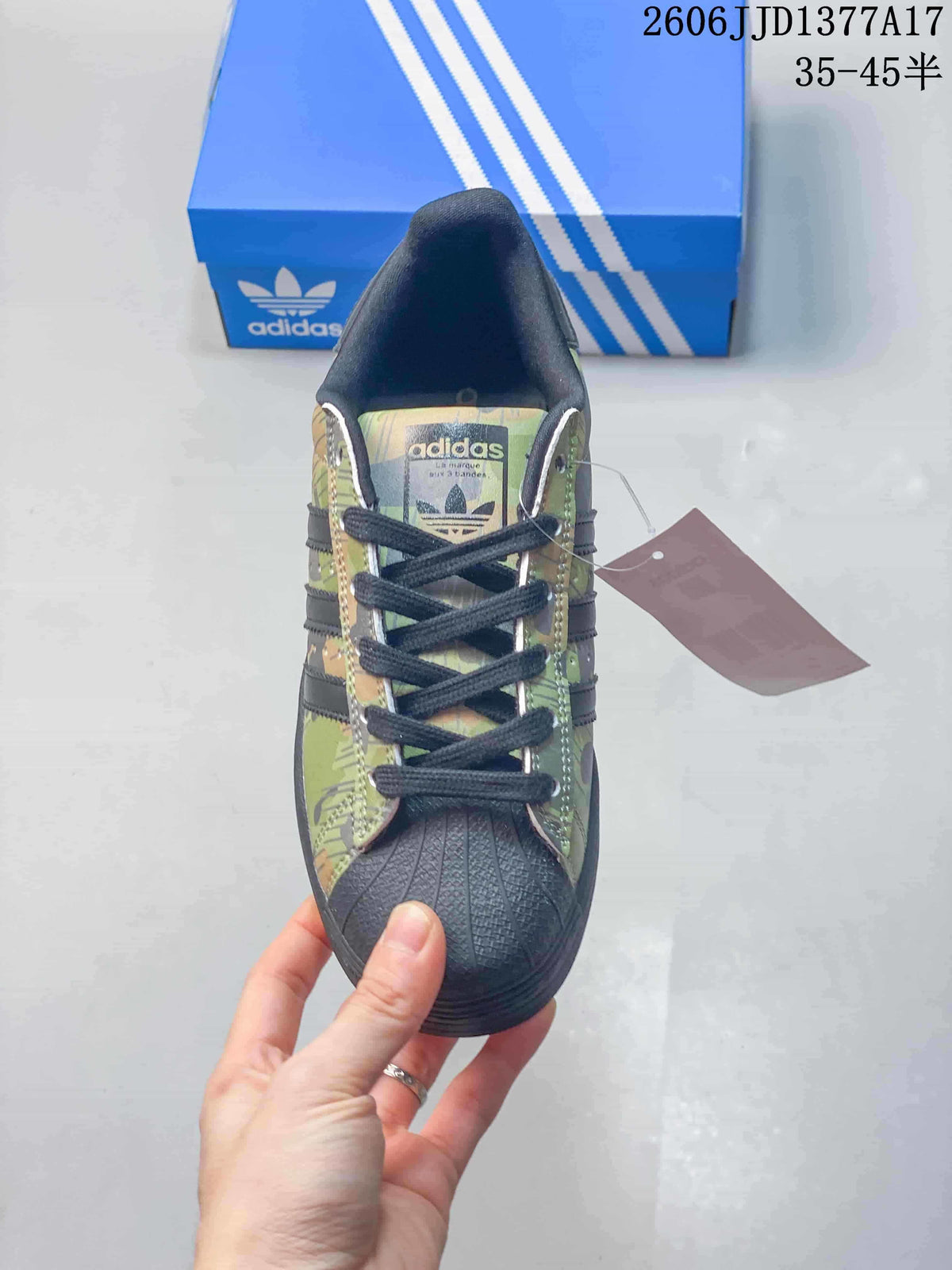 Front view of a camouflage Superstar sneaker with dark laces and a textured shell toe