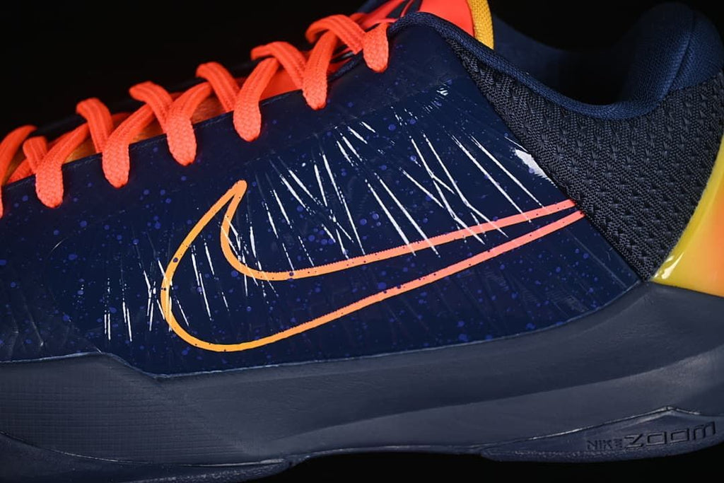 Close-up of the side Swoosh, navy upper, and coral laces.