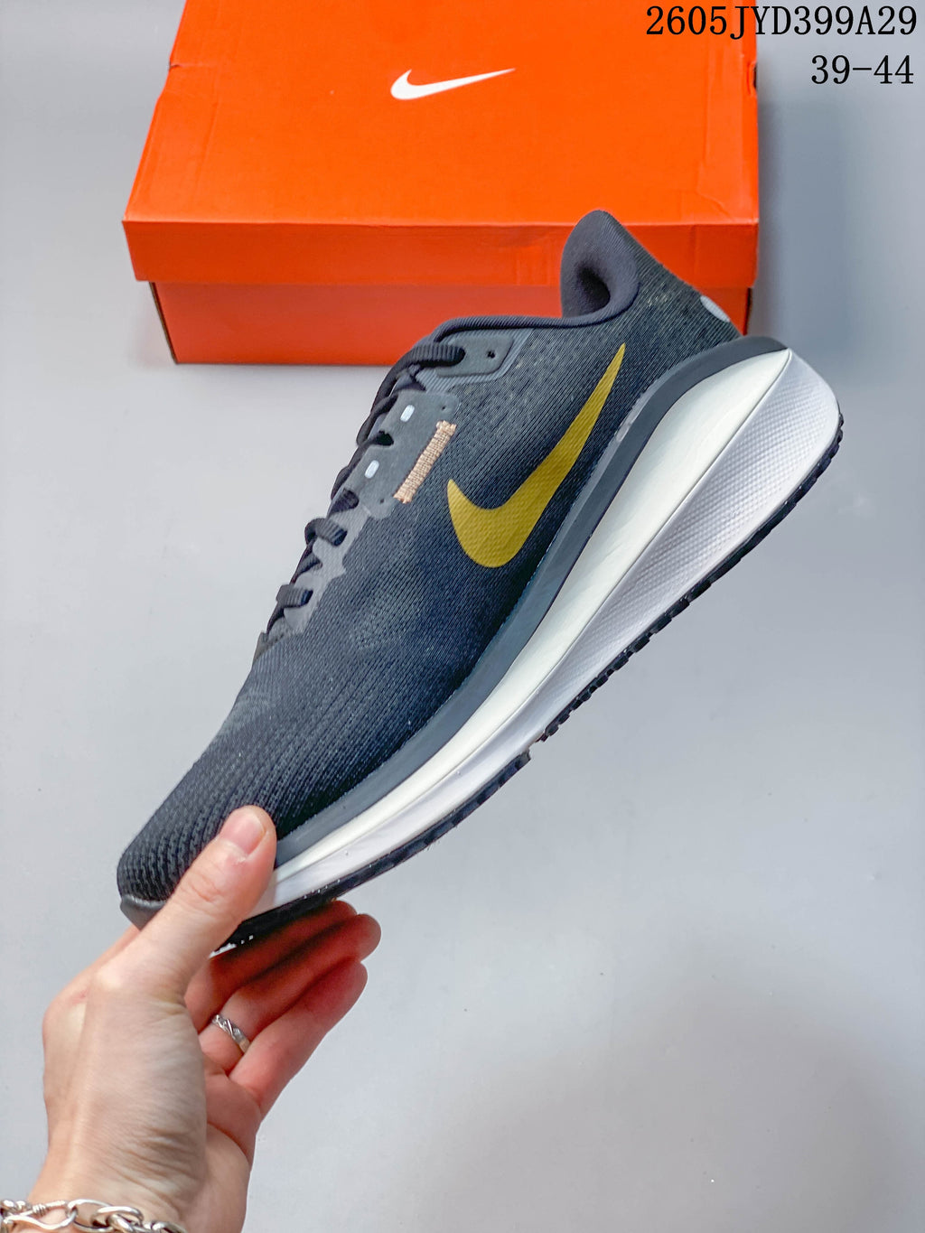 Side profile of a dark gray Nike running shoe with yellow side branding and a white midsole.