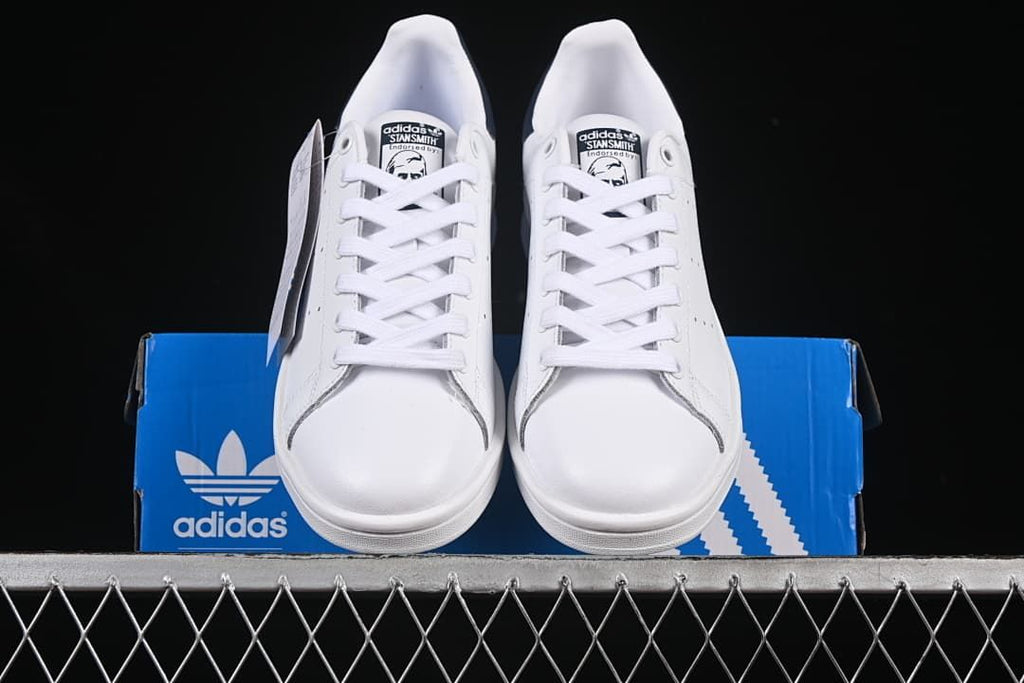 Front view of the pair of white lace-up sneakers on a blue box.