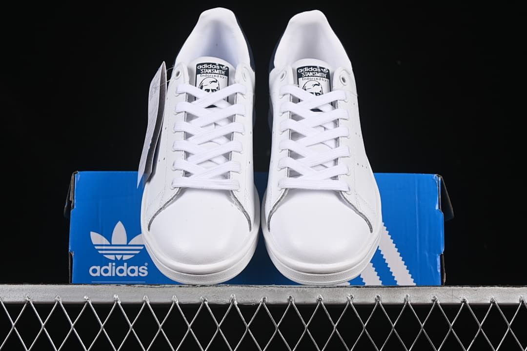 Front view of the pair of white lace-up sneakers on a blue box.