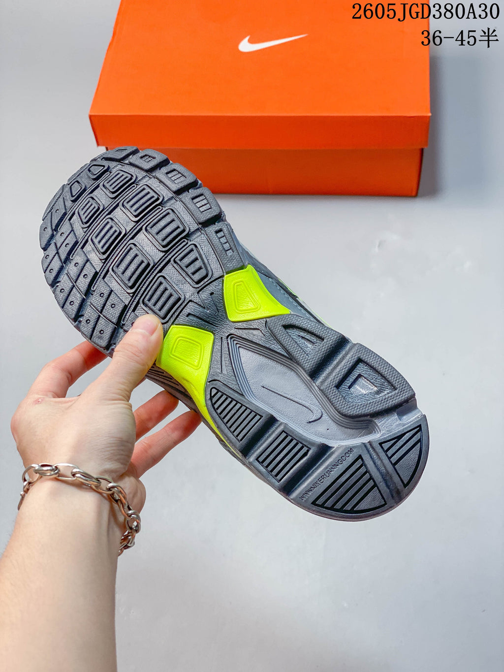 Underside view showing the sneakers' segmented tread pattern and gray and volt green outsole details.