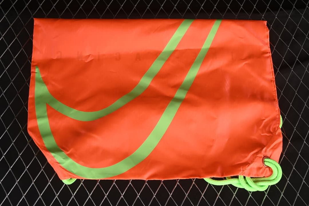 Bright orange-red drawstring shoe bag with a large green graphic