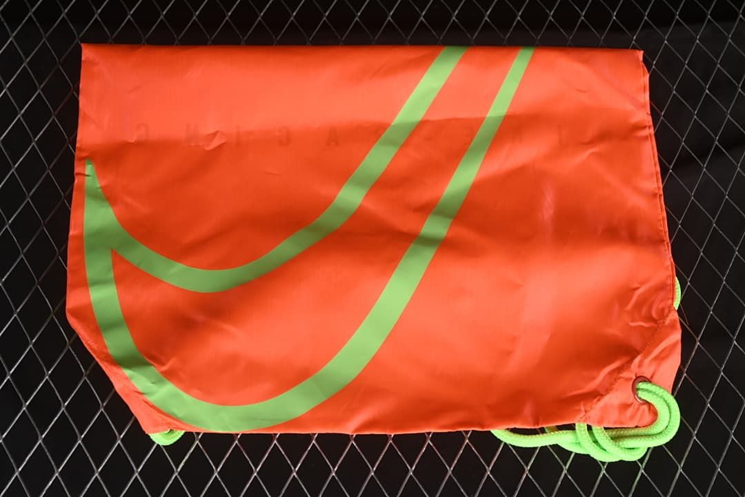 Bright orange-red drawstring shoe bag with a large green graphic