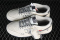 Pair of white and grey Nike SB Dunk Low sneakers with heart-patterned panels, patterned laces, and an additional pair of white laces.