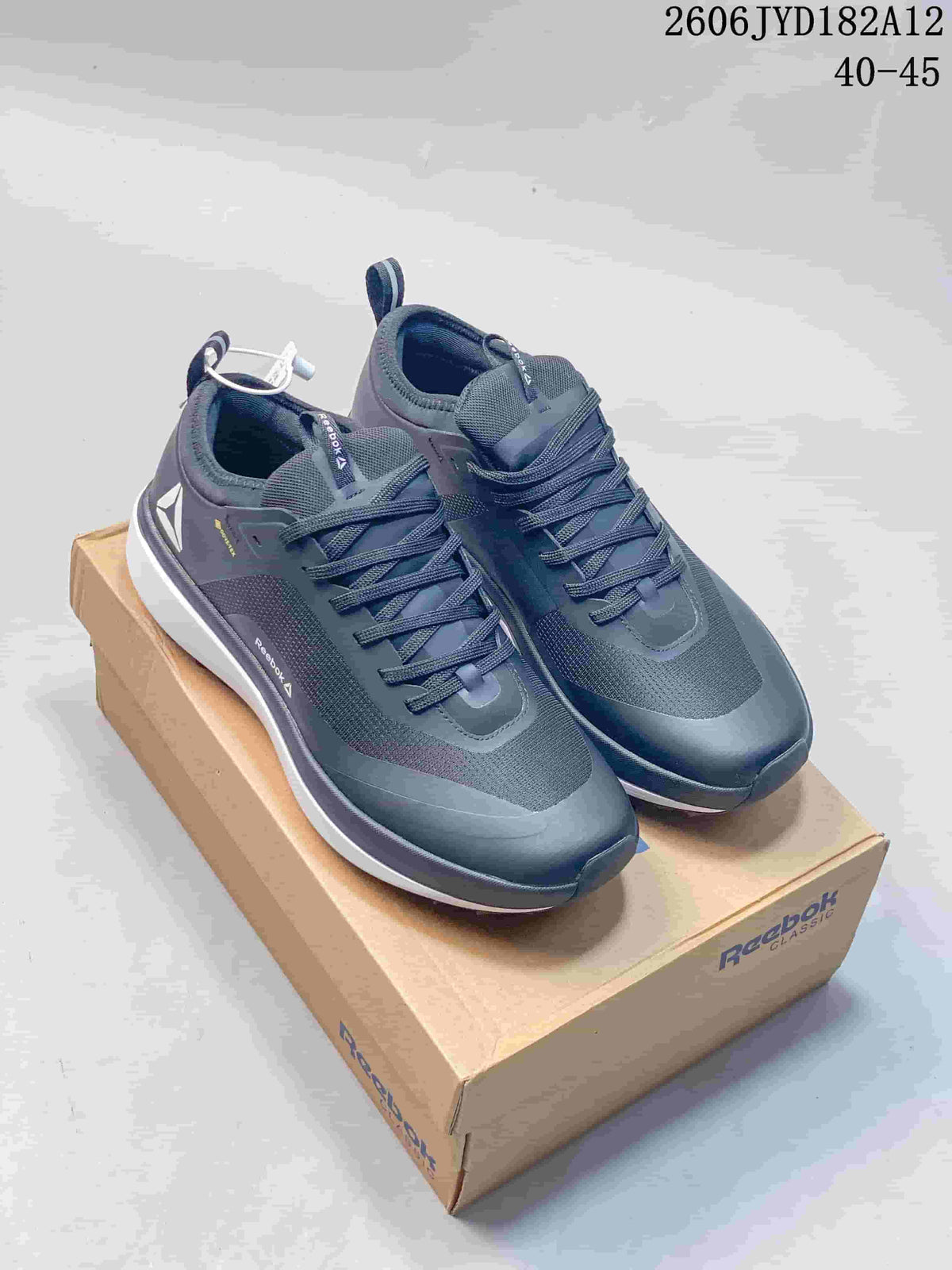 Pair of dark gray Reebok low-top sneakers displayed on a Reebok Classic box