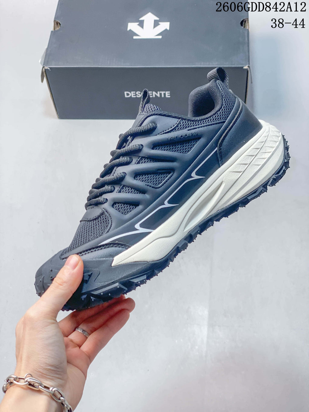 Side view of a gray DESCENTE sneaker with mesh-look panels, laces, and a contrasting midsole.