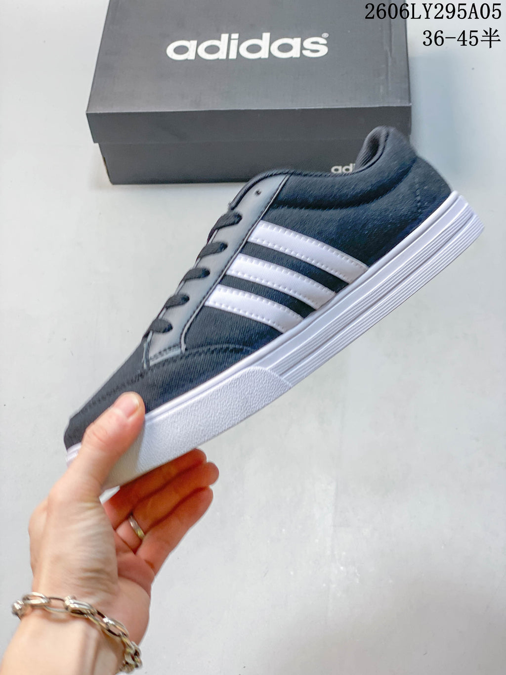 Side profile of a charcoal gray Adidas sneaker with three white stripes and a white sole.