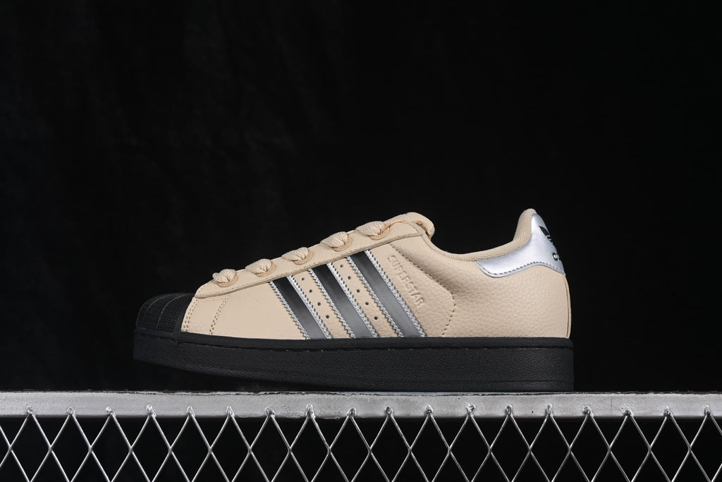 Opposite side profile showing the beige upper, silver three-stripe detailing, shell toe, and black outsole.