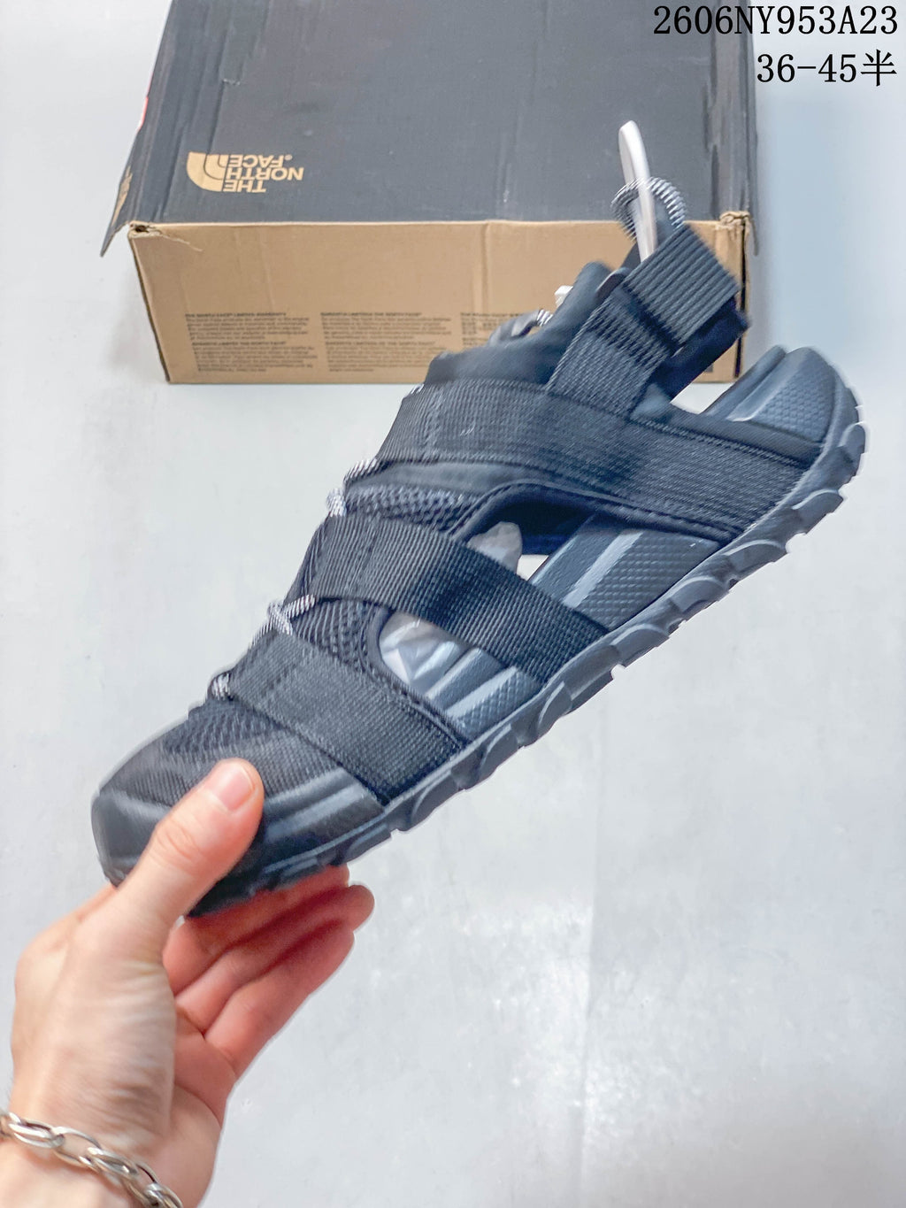 Side view of the black open-toe sandal with webbing straps and mesh panels.