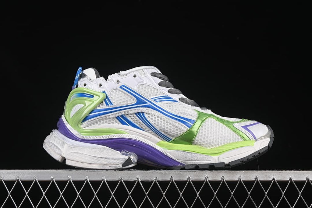 Side profile of the white sneaker with blue side graphics and green heel support