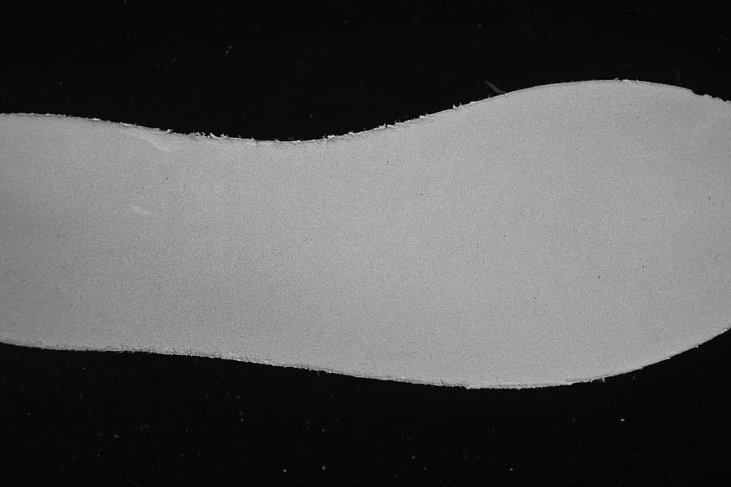 Close-up of a pale, textured shoe component against a dark background