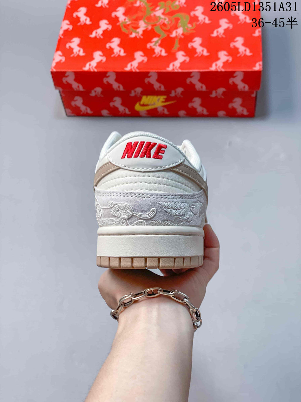 Rear view showing embroidered cloud motifs, taupe heel accents, and red Nike lettering