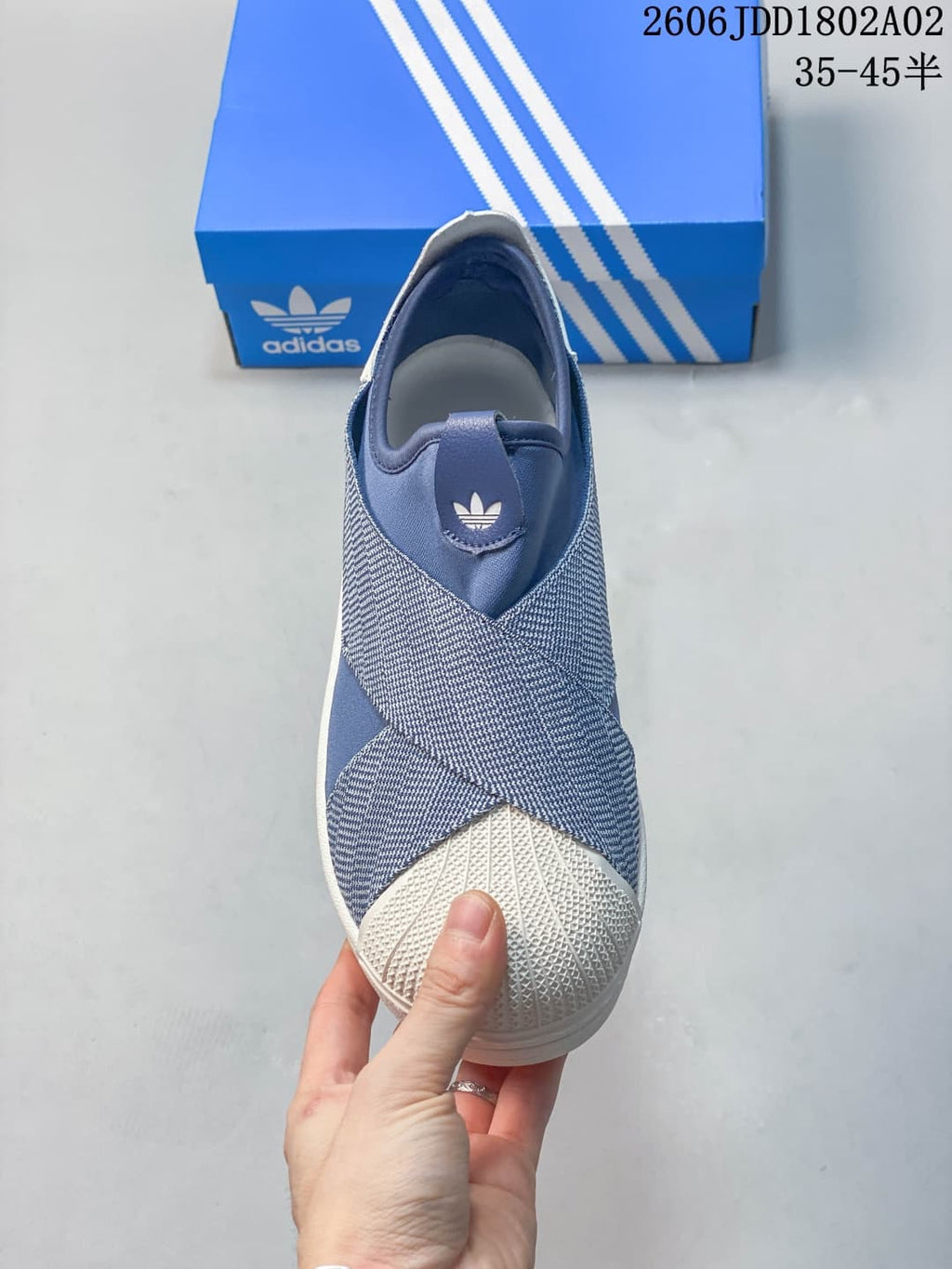 Top view of the blue and white slip-on sneaker showing the crossover upper panels, padded opening, Trefoil tongue logo, and shell toe.