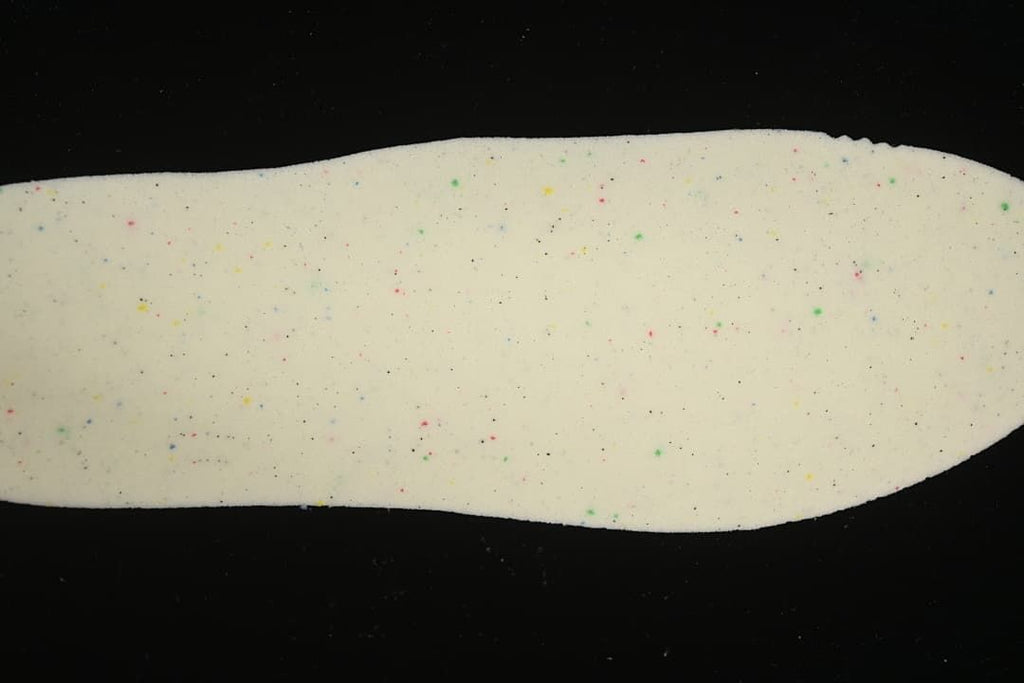 Close-up of a light-colored insole with scattered multicolor speckles