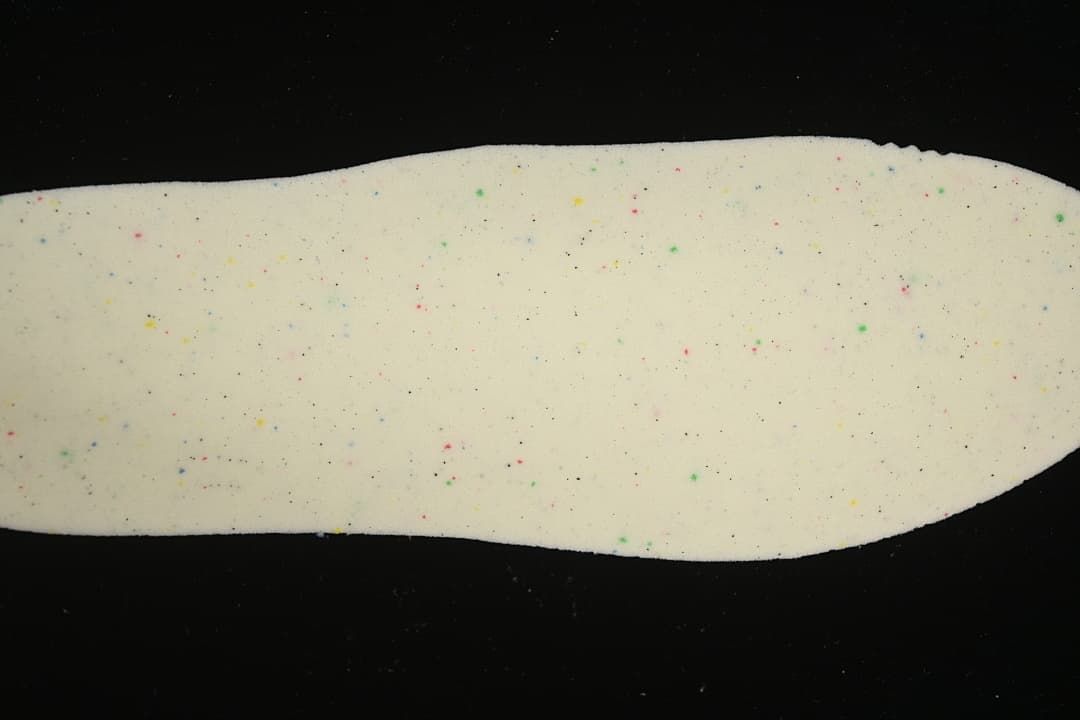 Close-up of a light-colored insole with scattered multicolor speckles
