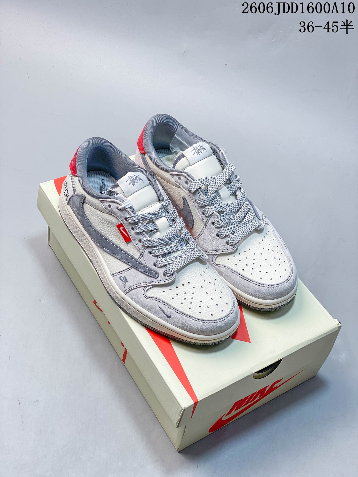 Pair of off-white and grey low-top sneakers with patterned laces and red heel accents on a shoebox.
