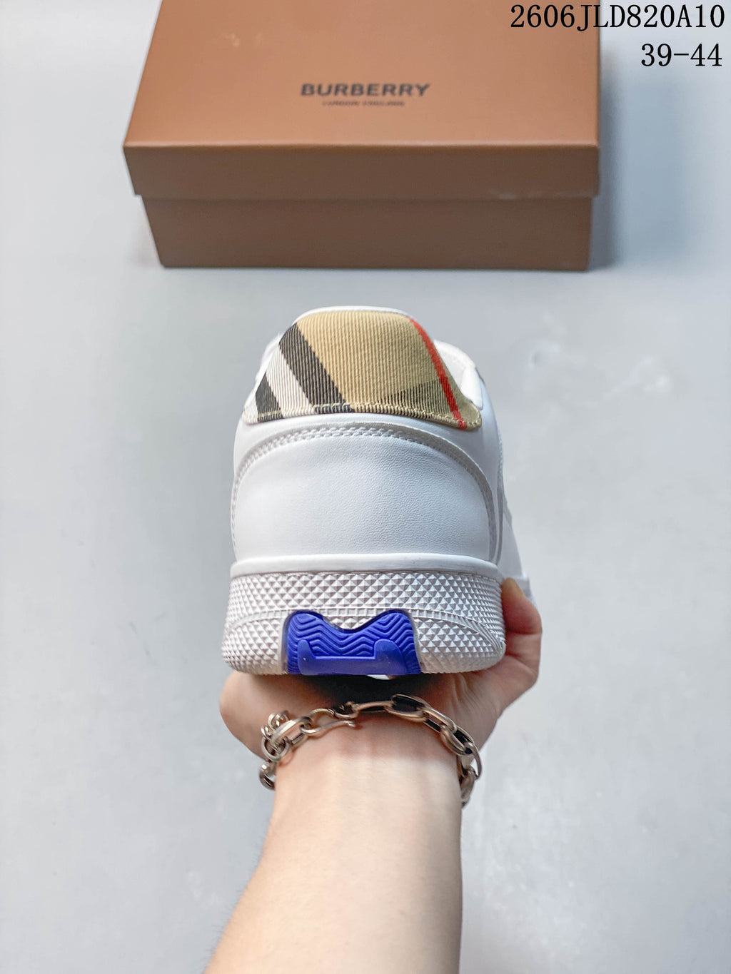Rear view of a white sneaker with a check-pattern heel tab and blue sole accent