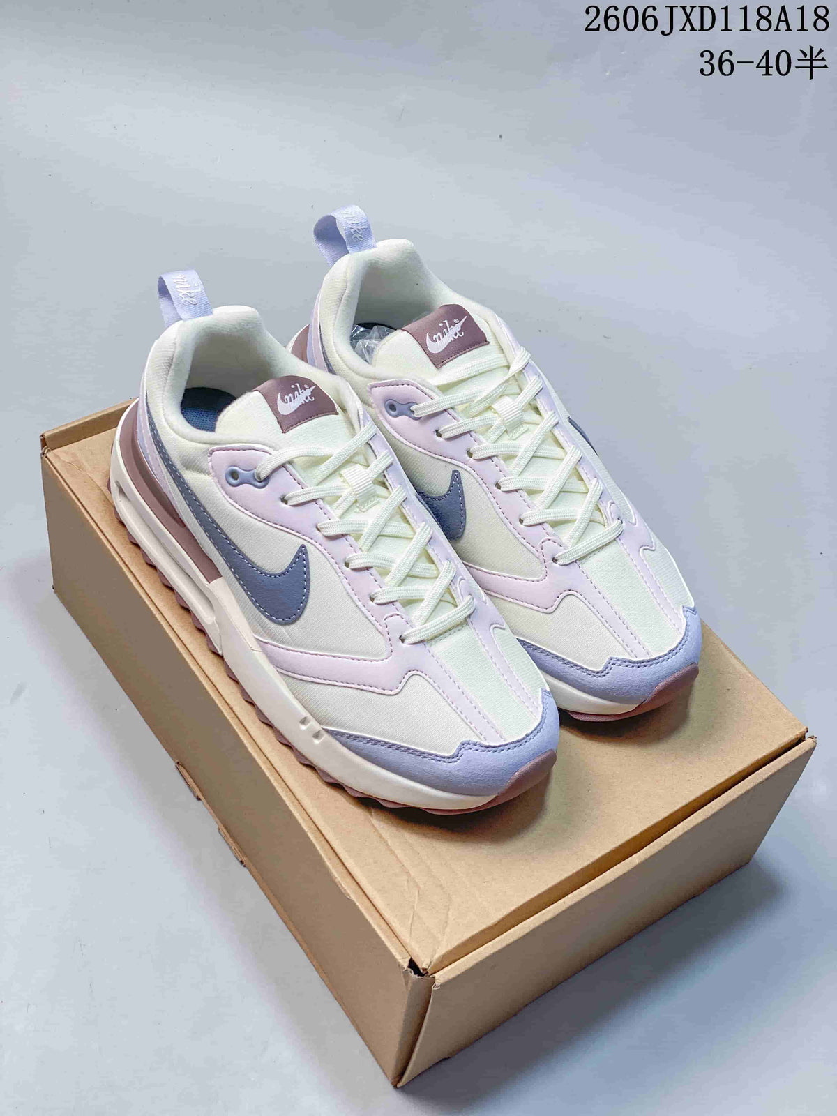 Pair of Nike Air Max Dawn sneakers in cream white, lavender, blue-gray, and mauve, shown on a box.