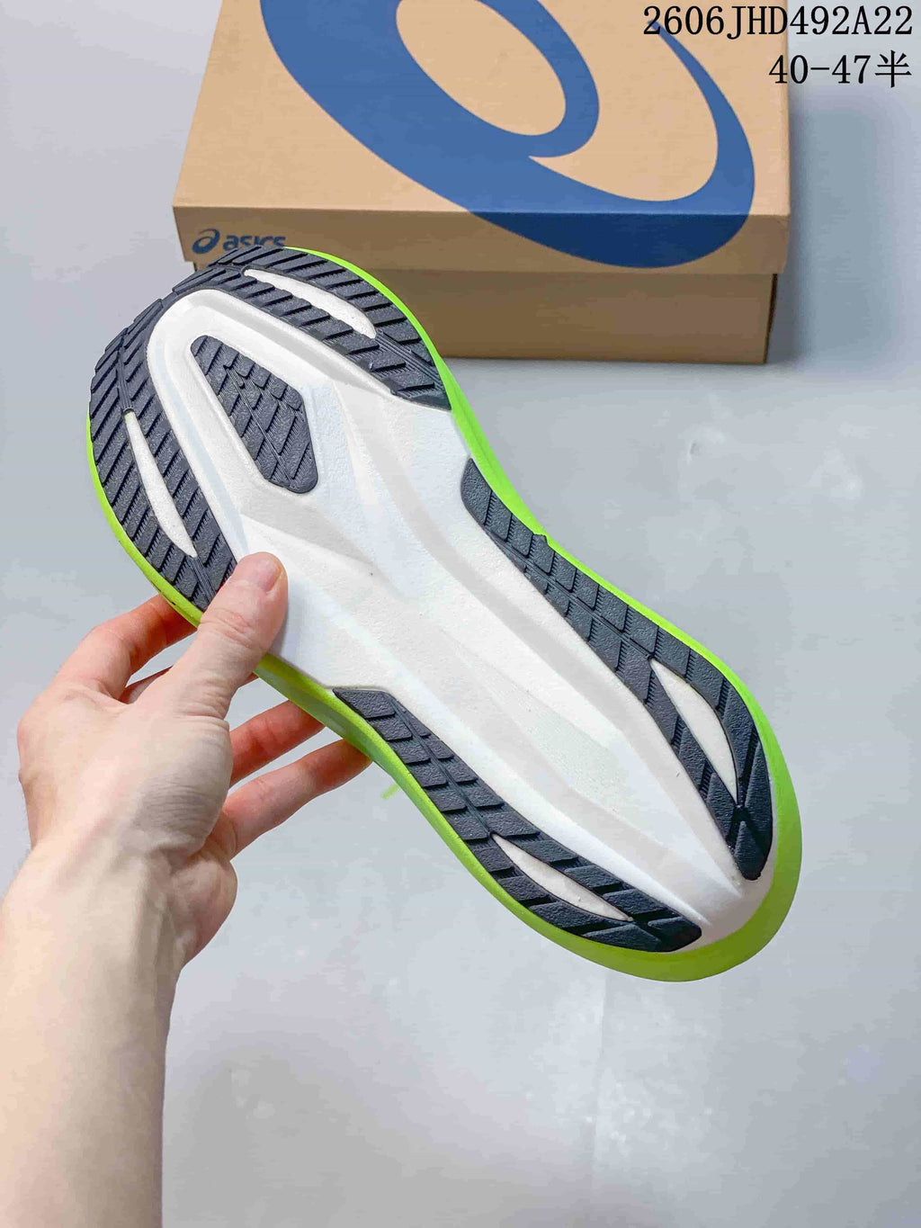 Underside of a running shoe showing a dark tread outsole and light-colored midsole