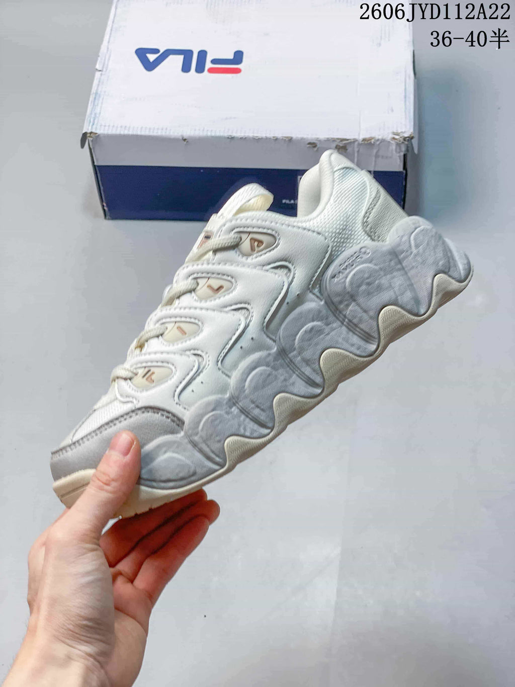 Side view of a white and grey FILA sneaker showing its layered panels