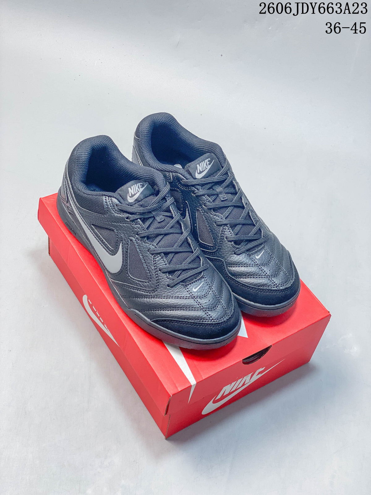 Pair of dark gray Nike Gato low-top sneakers displayed on a red shoebox