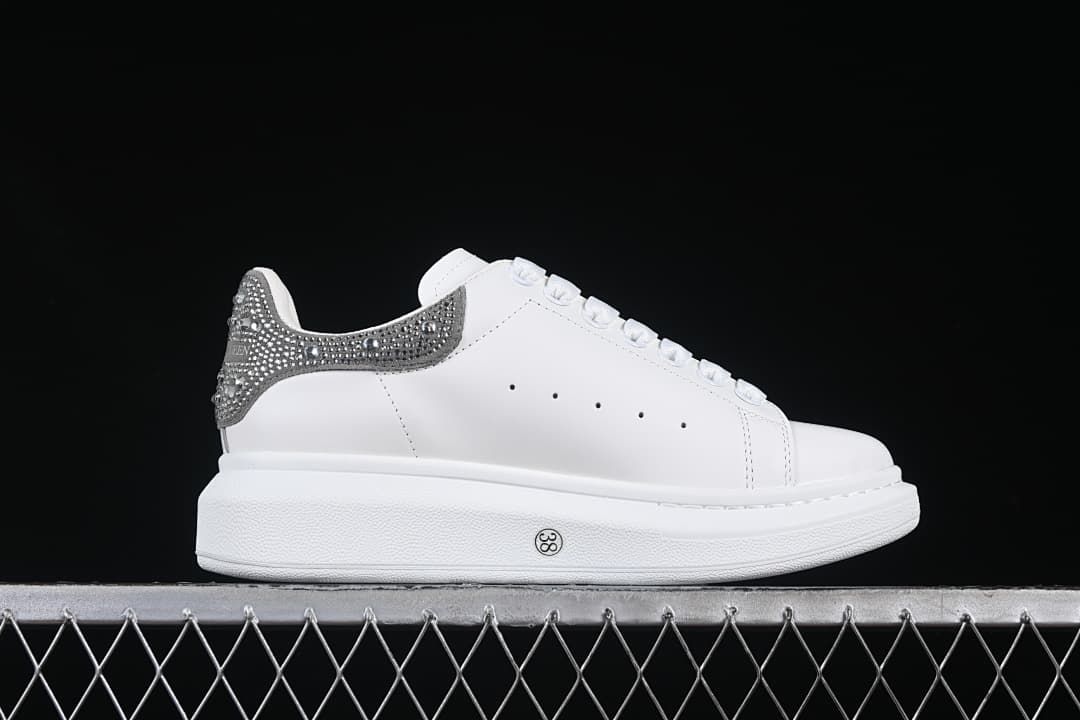 Side profile of the sneaker with a thick white sole and embellished heel.