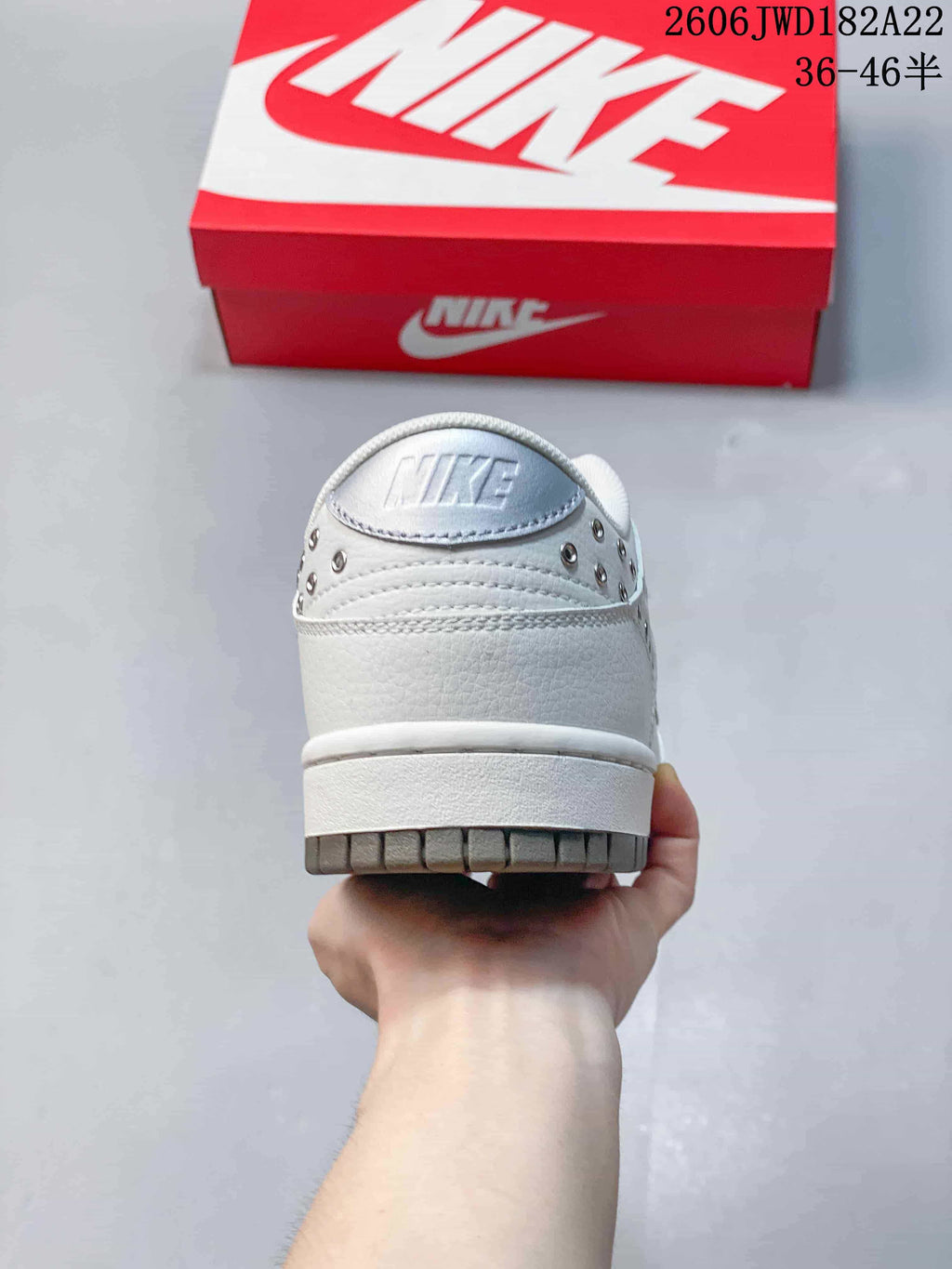 Rear view of a white low-top sneaker with silver-tone studs and a gray outsole