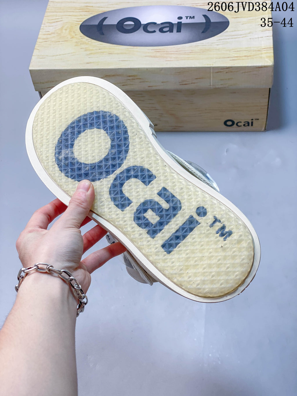 Translucent textured outsole with large Ocai lettering on a cream sneaker