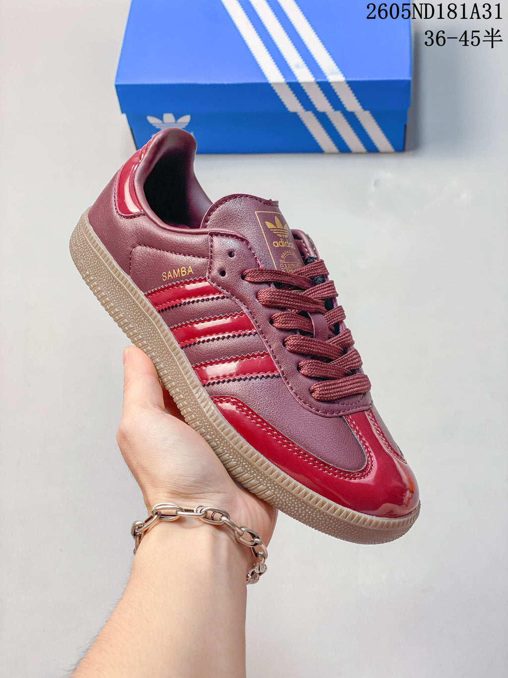Close side view of a burgundy and red sneaker with three stripes