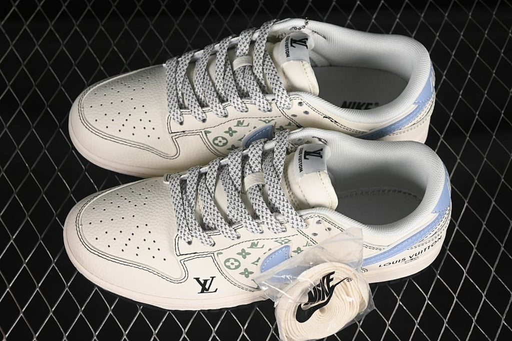 Pair of off-white low-top sneakers with light blue swooshes, green graphics and patterned laces; plain replacement laces are pictured