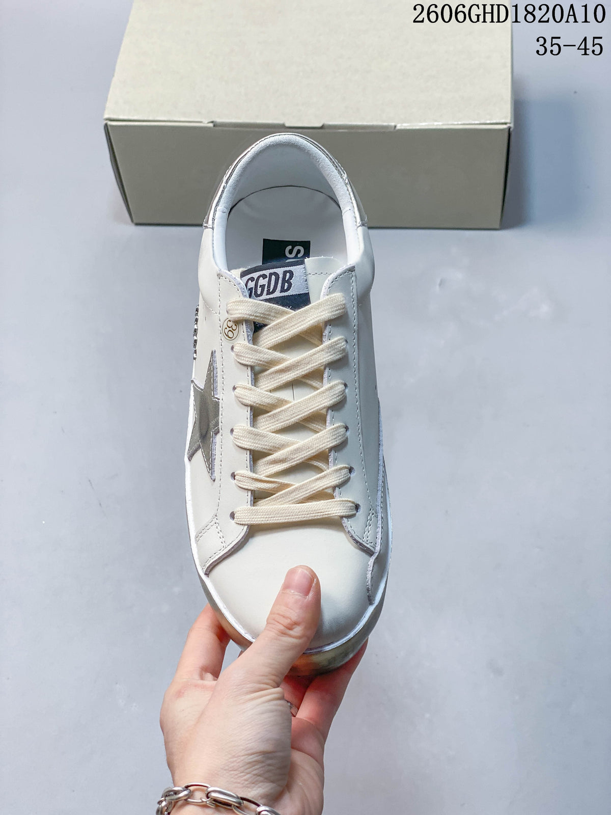 Top view of the sneaker showing cream-colored laces, white upper and silver star detail.