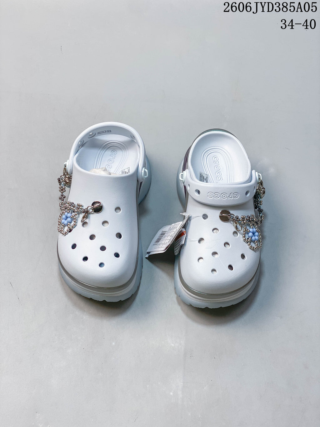 Pair of white platform clogs with decorative charms and adjustable heel straps.