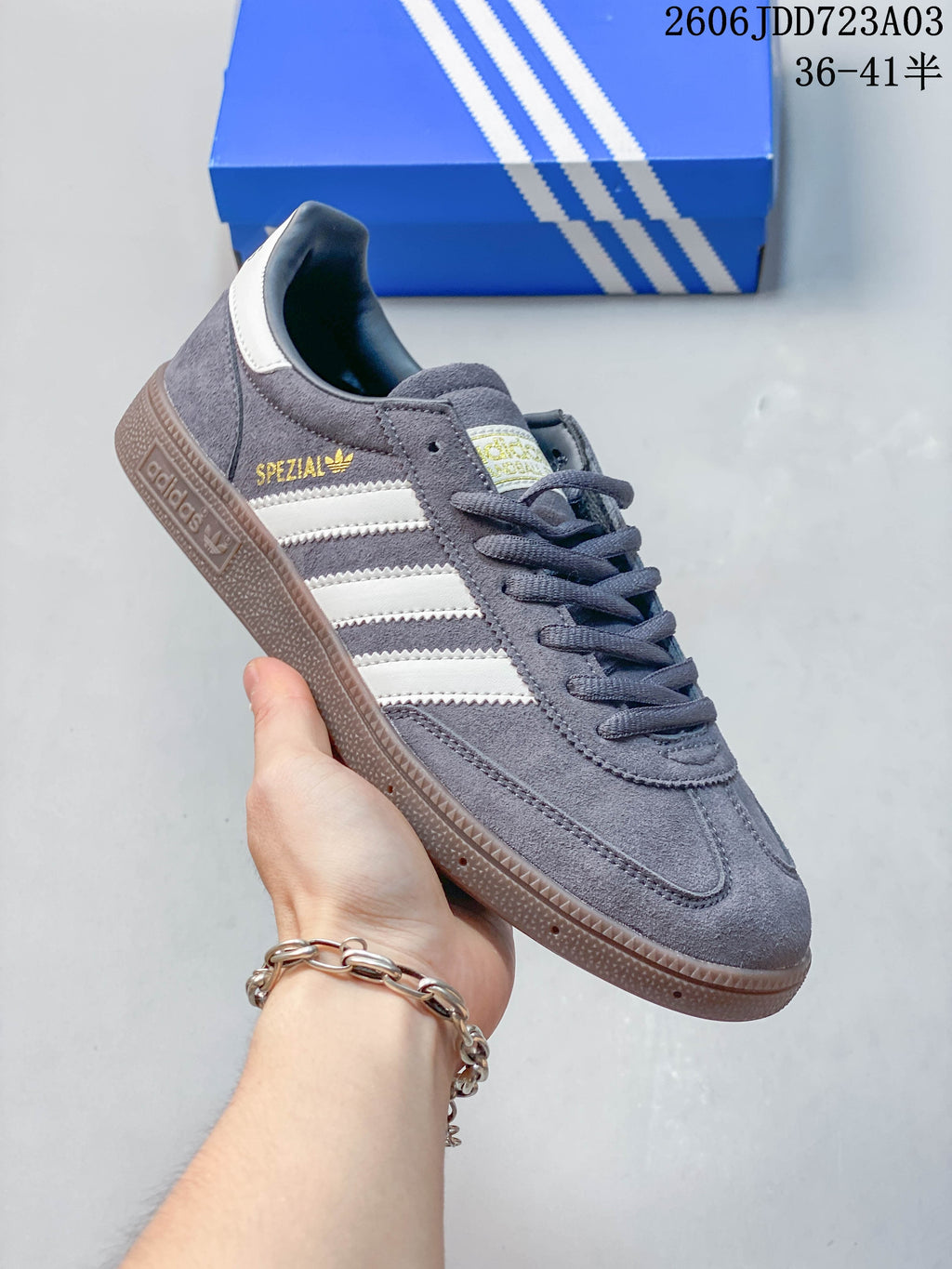 Side view of a slate gray Adidas Handball Spezial sneaker with pale stripes and a brown-toned outsole.