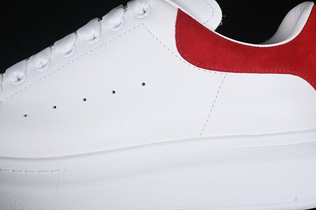 Close-up of the white side panel, perforations, laces, and red heel accent.