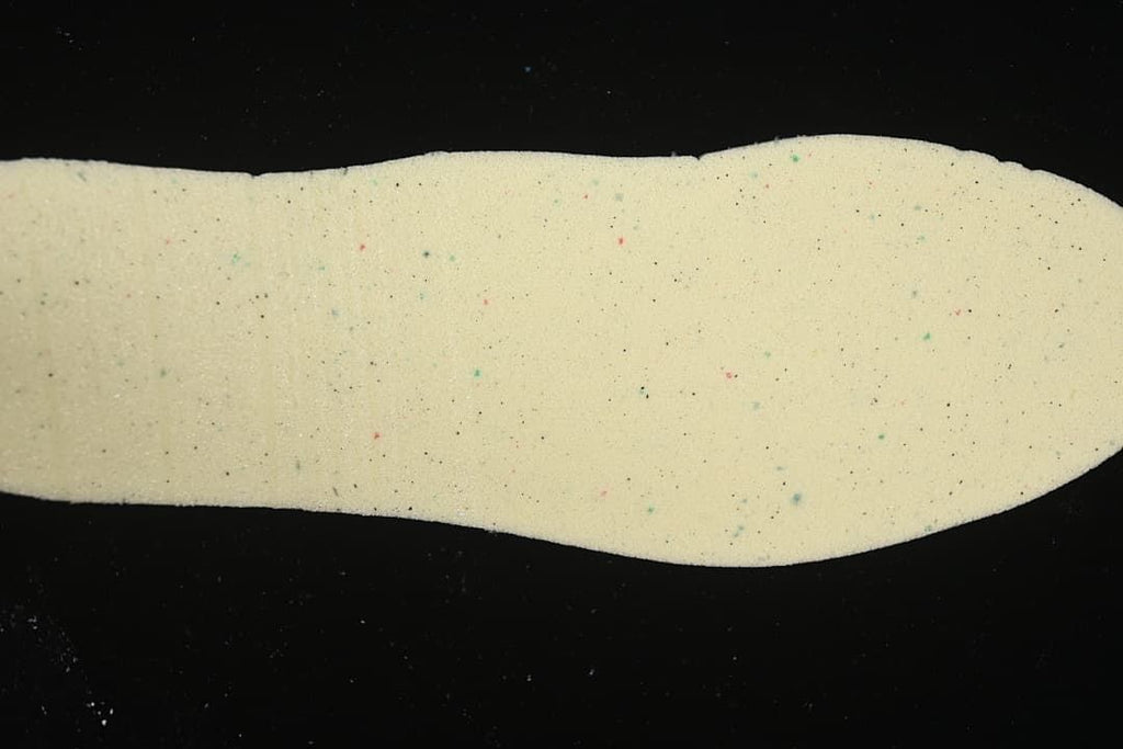 Close-up of a cream-colored shoe insole with small colored speckles.