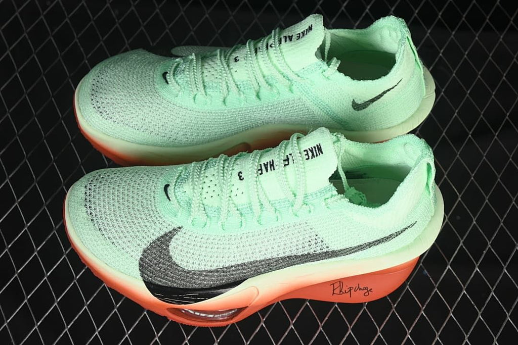Pair of mint-green running shoes with dark Swoosh details and coral-orange soles.