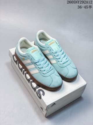 Pair of pale sea blue adidas sneakers with off-white stripes and gum-colored soles displayed on an adidas shoebox.