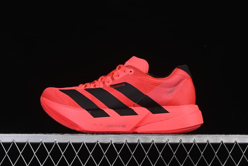 Side view of a coral Adidas Adizero running shoe with black stripes