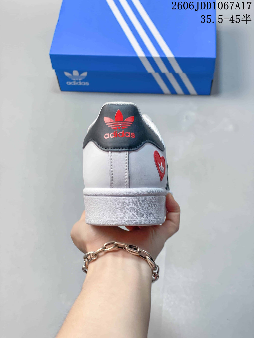 Rear view of a white sneaker with a dark heel tab and red logo detail