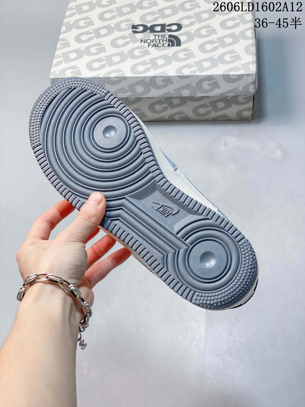 Close view of the grey circular-pattern outsole and branded shoe box.