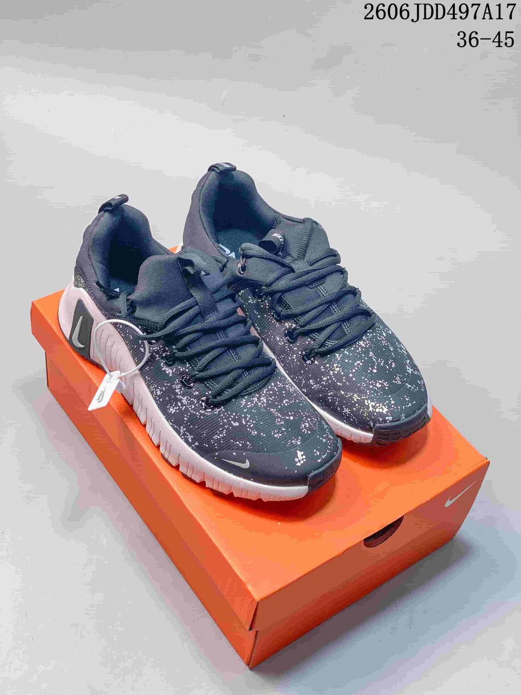 Pair of dark Nike Free Metcon 7 training shoes with speckled uppers and pale midsoles on an orange shoe box